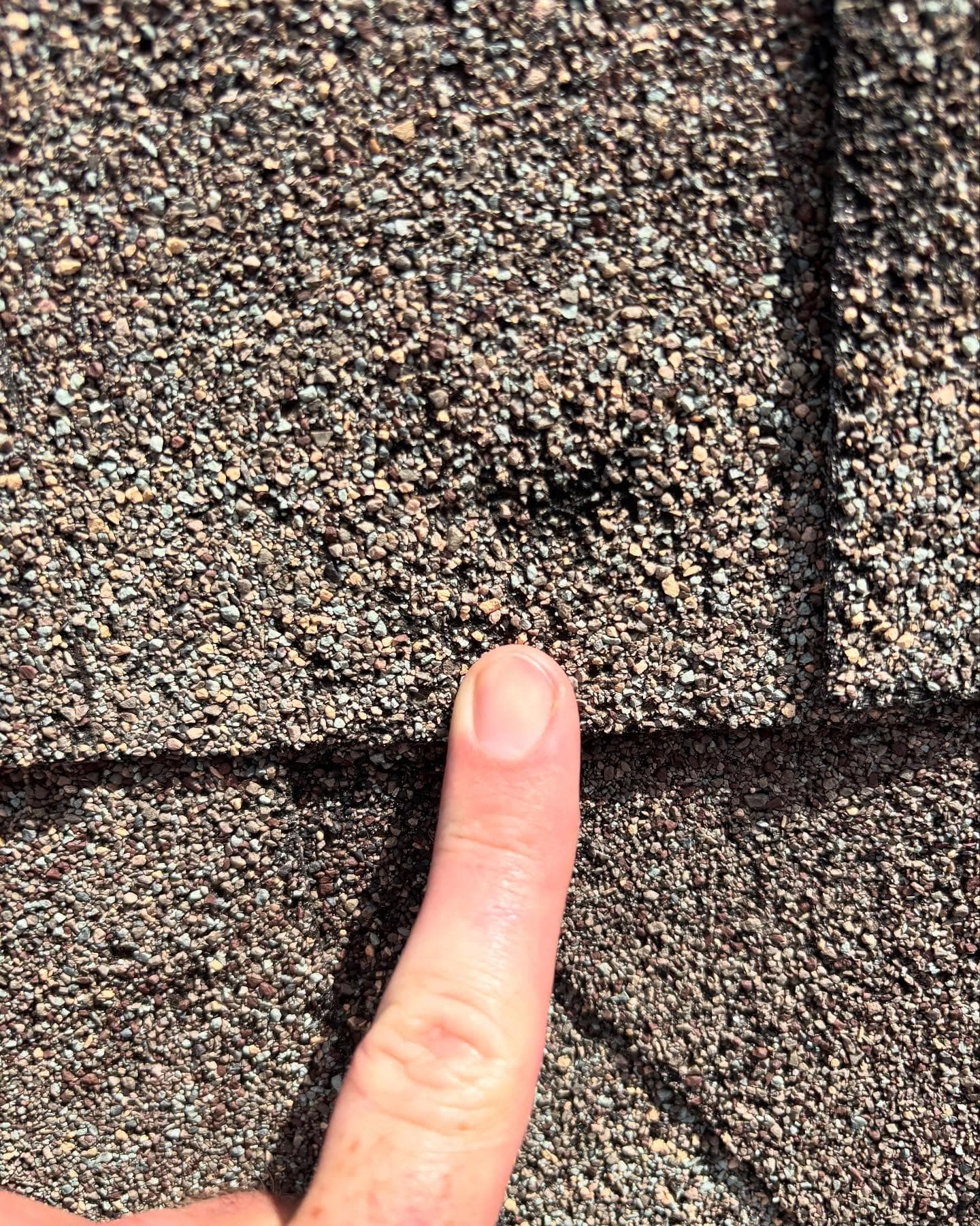 Hail damage indentation on an asphalt shingle during inspection