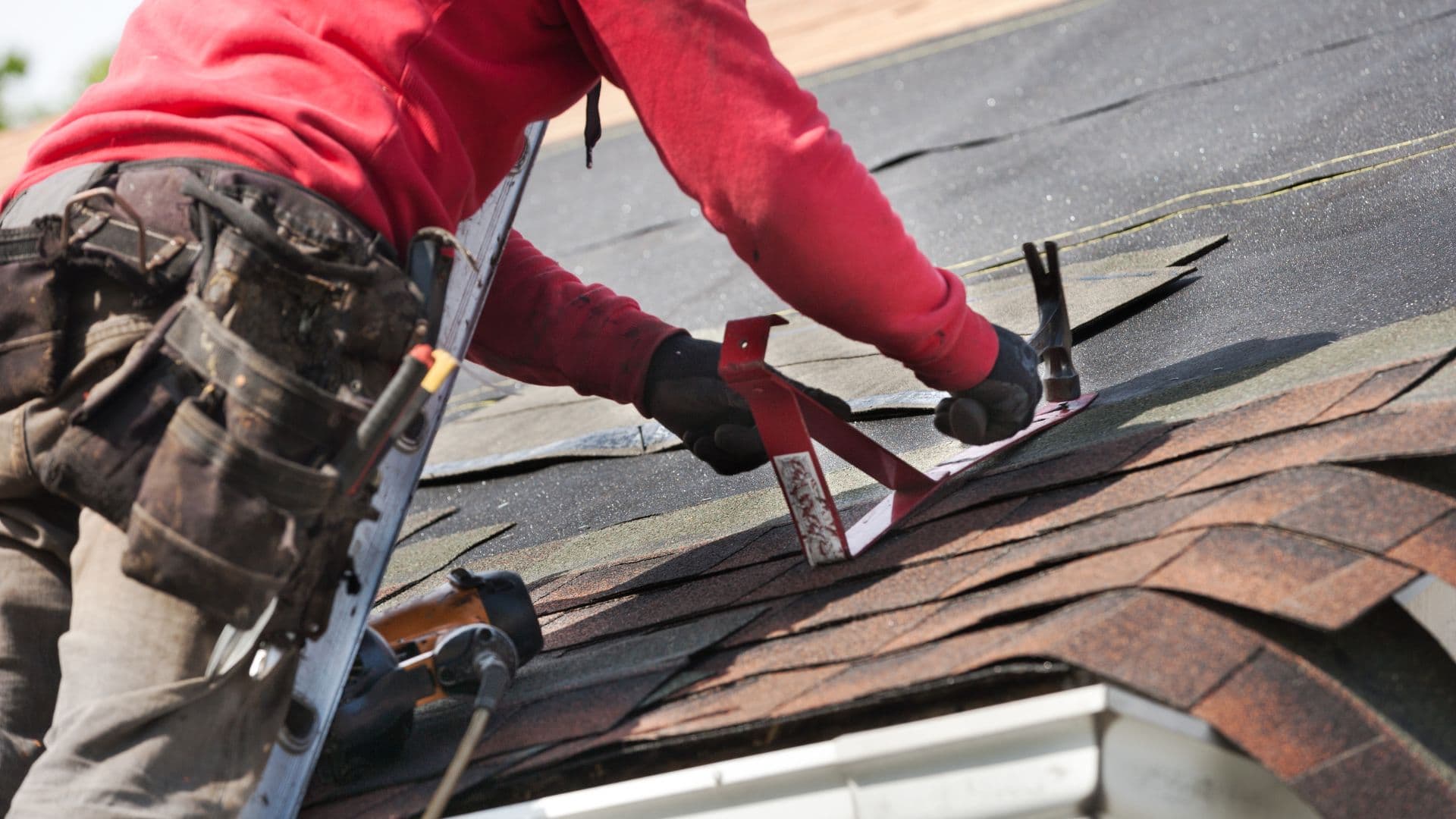 Roofer finishing shingle installation along a roof hip